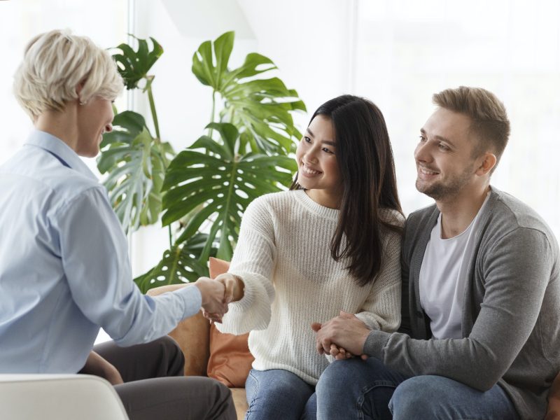 couple-shaking-hands-with-counselor-thankful-for-help-in-office